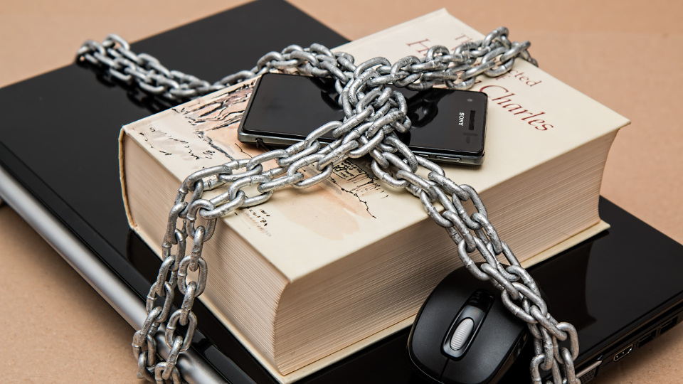 Laptop, book and phone in shackles